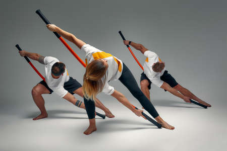 Two men and woman aikido fighters with wooden fight stick posing in studio, fight demonstrationの写真素材
