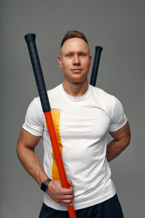 A fighter in white t-shirt and black shorts, stands in a fighting artificially pose and holds a...
