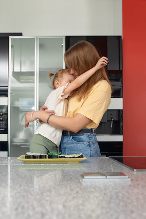 Beautiful caucasian mom and daughter eating rolls and sushi at family lunch at home. Delivery food. Traditional japanese food.の写真素材