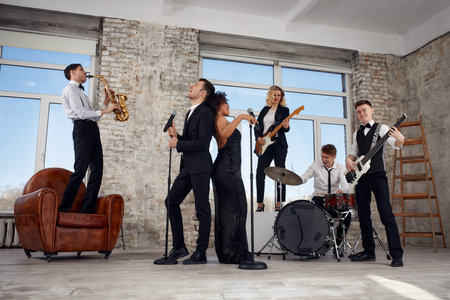 Repetition of multi ethnic jazz band in loft. Bass guitar player, electric guitar player,...