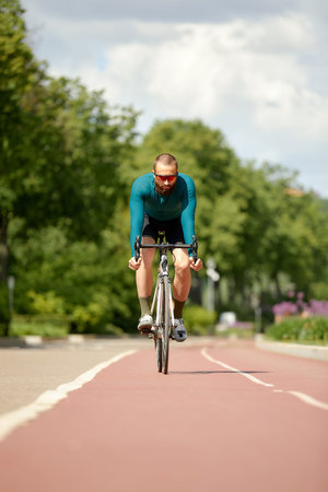 Portrait of a sporty man in a cycling outfit standing with a bicycle on the Bike Lane, posing for...