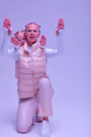 Woman with little girl in futuristic costume wearing smart led glasses of virtual reality while touching air. Augmented reality game, future technology, AI concept. VR. Neon light.の写真素材