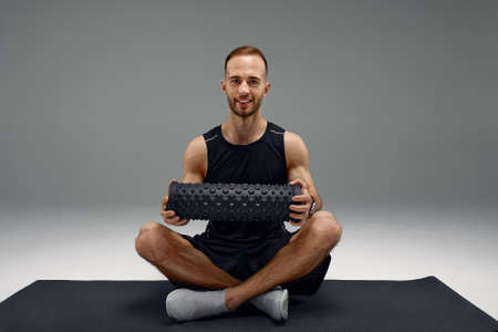 Athletic man using a foam roller to relieve sore muscles after a workout.の写真素材