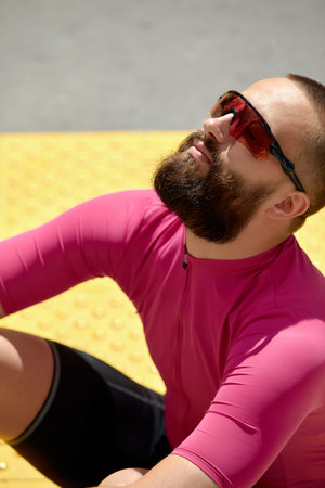 Portrait of a smiling fitness man resting while sitting on a ground at the track field outdoors
