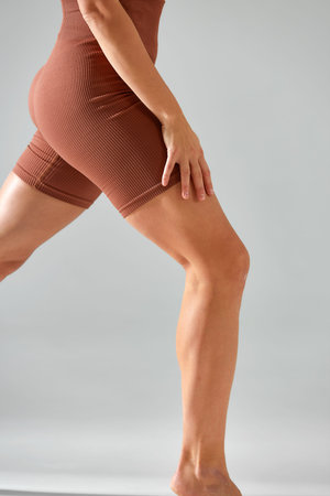 Croped shot of young woman with beautiful slim healthy body posing in studio. Legs close up. Fitness...