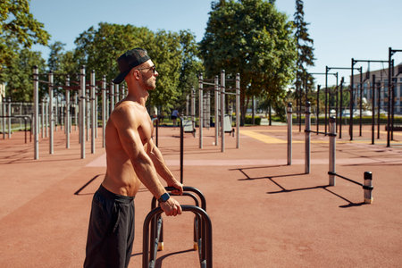 Handsome man on sport ground. The sportsman the guy, carries out difficult exercise, sports...