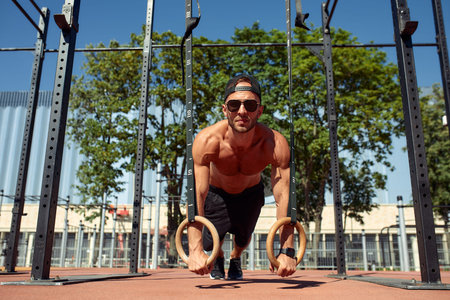 Handsome man on sport ground. The sportsman the guy, carries out difficult exercise, sports...