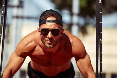 Young and handsome man is doing some push-ups. He is using loops for thatの写真素材