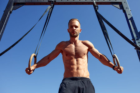 Handsome man on sport ground. The sportsman the guy, carries out difficult exercise, sports...