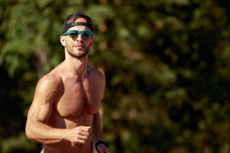 Urban sports. Sporty man shirtless jogging for fitness in the city park on a beautiful summer dayの写真素材