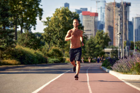 caucasian man jogging on the running track - Blonde male athlete in stadium training run in sunny spring or summer day - real people healthy lifestyle conceptの写真素材
