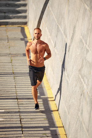 Young athlete man do morning run. Male runs up the stairs doing cardio exercises.