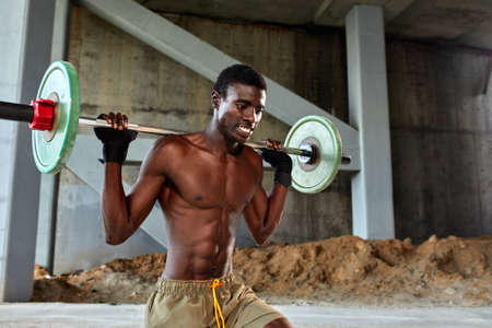 Athletic black young man lifting a heavy-weight barbell in outdoor gym under the bridge. Healthy lifestyle conceptの写真素材