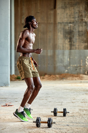 Attractive african american man smiling and doing exercise with dumbbells.