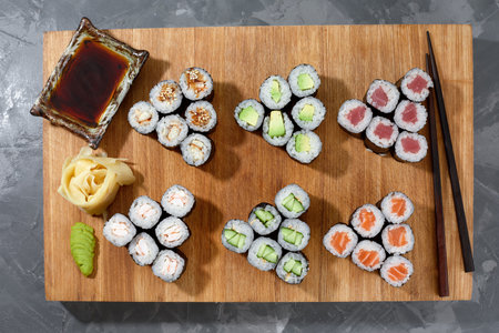 Different types of delicious and juicy sushi and rolls on a wooden boardの写真素材