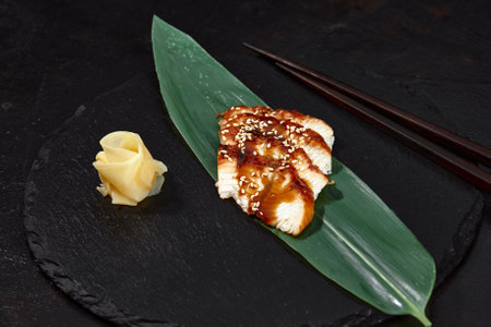 Fresh seafood sashimi smoked eel on slate board with wasabi and ginger on black backgroundの写真素材