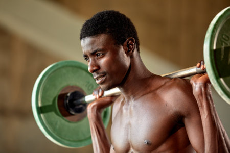 Athletic black young man lifting a heavy-weight barbell in outdoor gym under the bridge. Healthy lifestyle conceptの写真素材