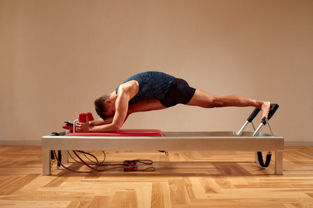 Fit man doing a lunge stretch yoga pilates exercise to strengthen and tone his muscles using a...