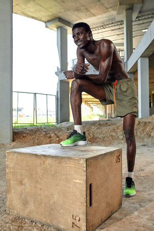 Handsome African American sportman standing on the street while taking break after training. Black male having rest after workoutの写真素材
