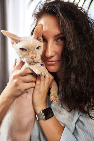 Portrait of young woman holding cute cat with blue eyes. Female hugging her cute short hair kitty....