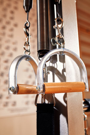 Fit man doing a lunge stretch yoga pilates exercise to strengthen and tone his muscles using a reformer in a gymの写真素材