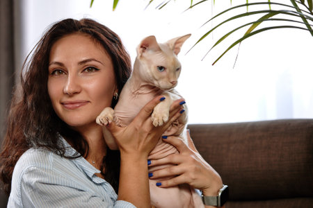 Portrait of young woman holding cute cat with blue eyes. Female hugging her cute short hair kitty. Background, copy space, close up. Adorable domestic pet concept.の写真素材