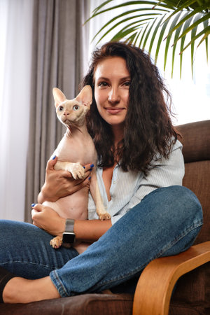 Portrait of young woman holding cute cat with blue eyes. Female hugging her cute short hair kitty. Background, copy space, close up. Adorable domestic pet concept.の写真素材