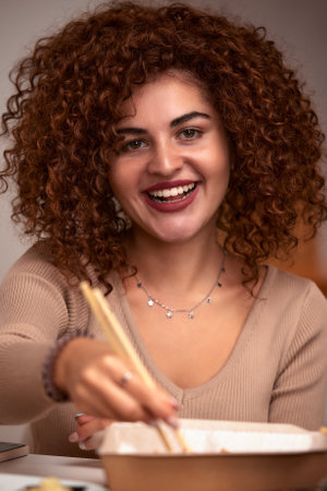 Young woman eating sushi asian food and noodles using choopsticks from take away deliveryの写真素材
