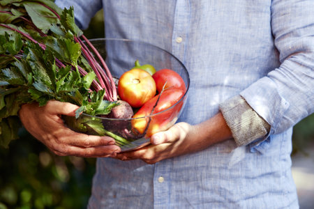 Happy farmer with a basket full of seasonal vegetables.の写真素材