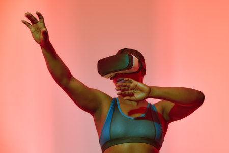 African american woman streamer playing video game using virtual reality glasses at gaming roomの写真素材
