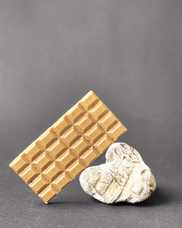 Bar of white chocolate on stone gray background. Side view. Place for text
