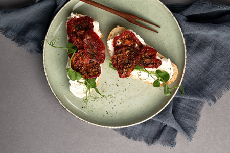 Bruschetta with sun-dried tomatoes, cream cheese and fresh vegetables. Healthy and wholesome food. Serving food in a restaurant. Photo for the menu.の写真素材