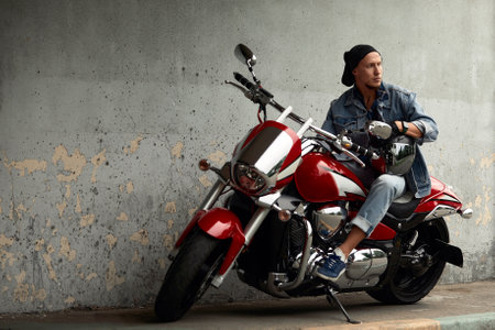 Handsome bearded biker with red motorcycle in classic style. Cafe racer in the garage.の写真素材