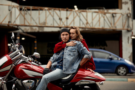 A young couple of bikers sits hugging on a motorcycle.の写真素材