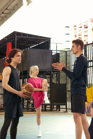 Young guys playing basketball, posing for the camera on the city basketball court, lifestyle active leisure young people.の写真素材