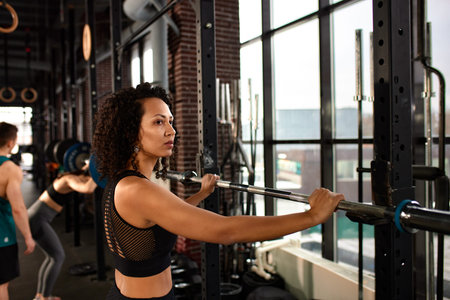 Athletic african american woman in crossfit gym close up smiling leaning on a barbell.の写真素材