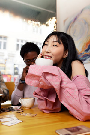 Cute mixed race couple of teenagers enjoying milkshake at cafeteria, first date