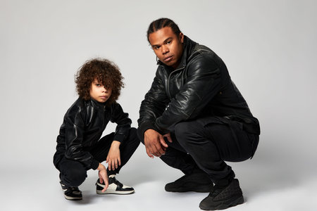 Father and son on a white background, African American father and son sitting on a white background