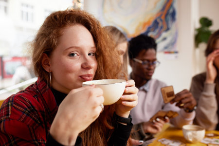 Multiethnic company of young people drinking coffee and playing games, looking at smartphones, taking selfies.の写真素材