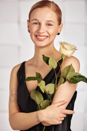 Beautiful young with special needs woman with flowers in her hand holding a flower, woman in black dress. Diversity women with disability and flowers.の写真素材
