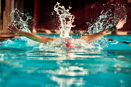 A man with a red cap swims in a blue pool, head-on shotの写真素材