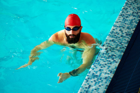 Swimmer athlete man resting at the side of the pool taking a break during training swims, swimming in the pool, training in the waterの写真素材