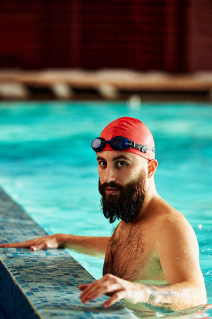 Swimmer athlete man resting at the side of the pool taking a break during training swims, swimming in the pool, training in the waterの写真素材