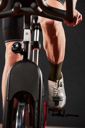 Legs and arms of a man on an exercise bike close-upの写真素材