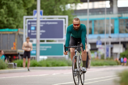 A cyclist man rides a bike in a city park along a bike path.の写真素材