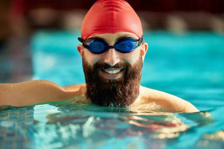 Portrait of a healthy smiling swimmer in the pool wearing goggles and a swimming capの写真素材