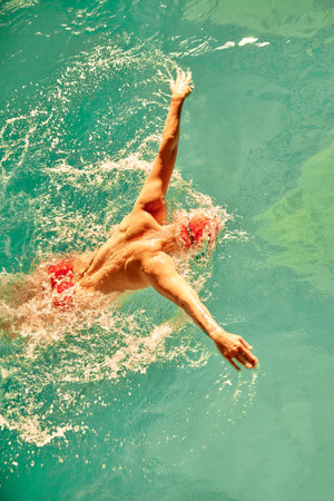 A male swimmer is training in the pool, a top view of a swimmer swimming along the track in the pool.の写真素材