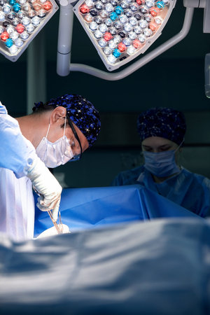 Portrait of a surgeon in the operating room against the background of a lamp, the doctor performs an...