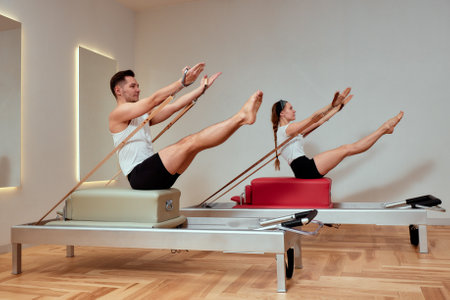A man and a woman in a pair do pilates exercises on reformers, diversity man and woman, paired exercises on a reformer to restore the musculoskeletal system, pilate, reformerの写真素材