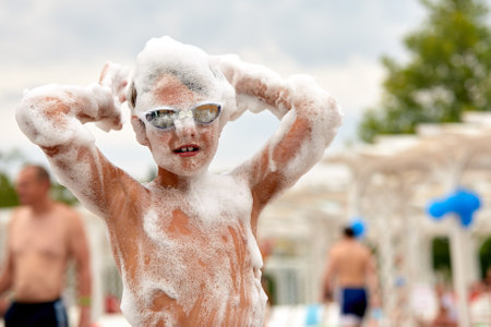 Face of a child in foam enthusiastic joyful child at a foam party, close-up of a child among the foam, baby foam party.の写真素材